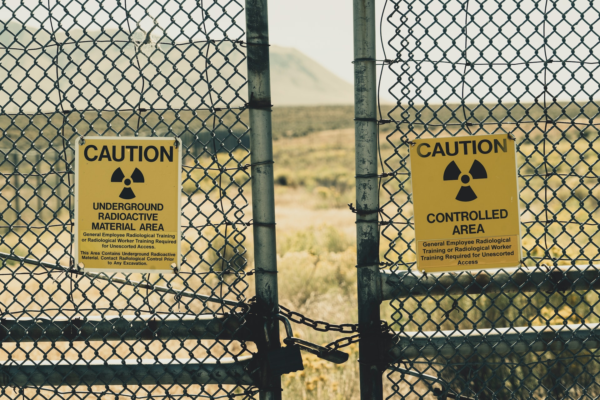 A bright yellow caution sign with black letters that says Underground radioactive material area and controlled area